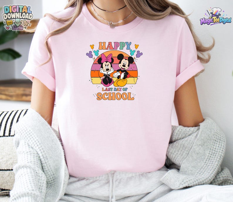 May include: A light pink t-shirt featuring a graphic of Minnie and Mickey Mouse sitting in front of a sunset. The text reads "HAPPY LAST DAY OF SCHOOL" in orange and blue letters, surrounded by small colorful Mickey-shaped balloon icons.