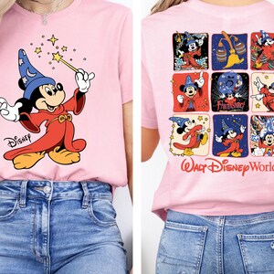 May include: Pink t-shirt featuring a graphic of Mickey Mouse as a sorcerer with a blue hat and red robe, holding a wand. The back of the shirt displays Mickey Mouse in various poses with the text "Walt Disney World".