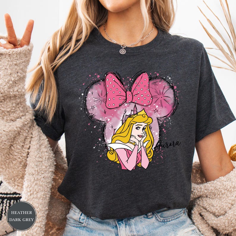 May include: Dark grey t-shirt with a Minnie Mouse-shaped design, a pink bow, and a princess illustration. The design includes the name "Aurora". A comfortable, casual wear t-shirt.