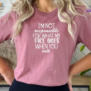 Könnte beinhalten: Ein malvenfarbenes Kurzarm-T-Shirt mit weißem Textaufdruck I'M NOT responsible FOR WHAT MY FACE DOES WHEN YOU talk. Das Shirt hat einen Rundhalsausschnitt und eine normale Passform, wobei die Botschaft deutlich auf der Brust zu sehen ist.