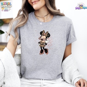 May include: A heather grey short-sleeve t-shirt featuring a graphic of a cartoon mouse character wearing leopard print clothing and pink glittery sunglasses, with a subtle pink paint splatter effect surrounding the character design.