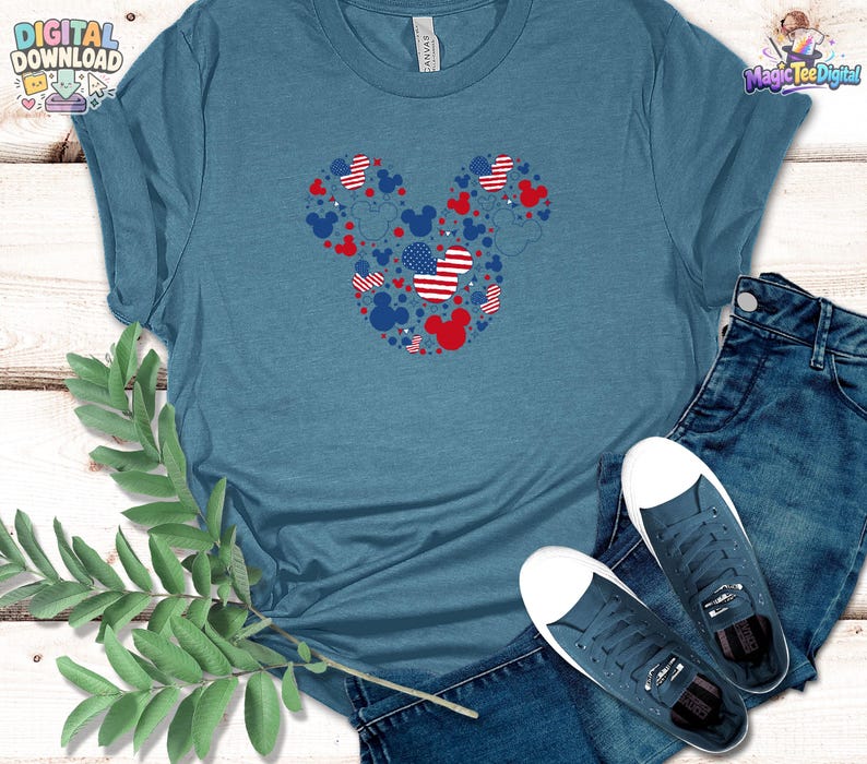 Puede incluir: Una camiseta de cuello redondo en color azul jaspeado con un gr&aacute;fico grande de la silueta de la cabeza de Mickey Mouse compuesta por iconos rojos, blancos y azules, incluyendo patrones de estrellas y rayas, junto a vaqueros azul oscuro y zapatillas.