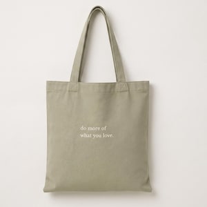 Könnte beinhalten: Eine hellgrüne Tragetasche mit passenden Griffen. Auf der Tasche steht in weißer, minimalistischer Schrift der Text "do more of what you love". Die Tasche ist aus robustem Stoff gefertigt und zum Tragen von Gegenständen bestimmt.