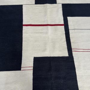 Close-up of geometric kilim rug showing black and cream Bauhaus inspired blocks with textured handmade wool flatweave detail
