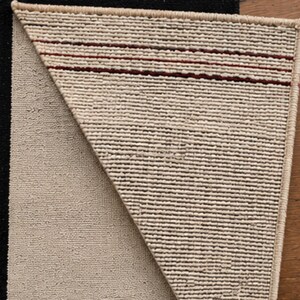 Detailed view of the geometric rug's folded corner and woven structure, showcasing the craftsmanship, texture, and clean edge finishing of the handmade wool rug.