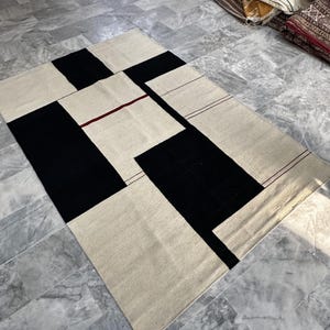 Modern geometric wool kilim rug styled in a living room with minimalist furniture and soft natural lighting