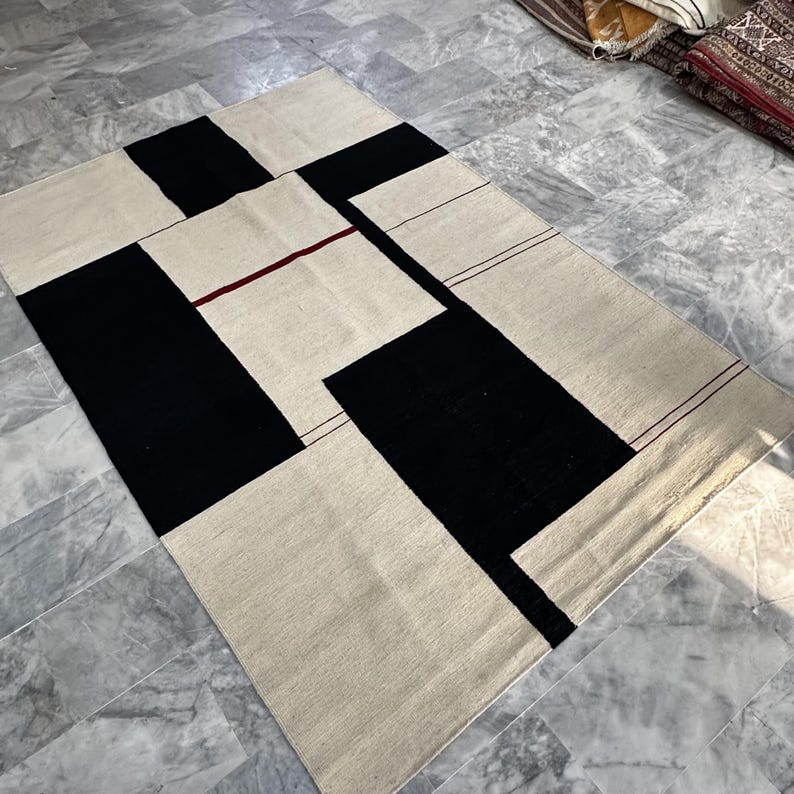 Modern geometric wool kilim rug styled in a living room with minimalist furniture and soft natural lighting