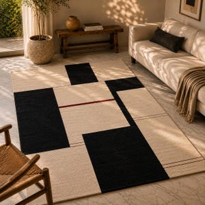 Handwoven Bauhaus-inspired geometric wool rug in cream, black, and burgundy tones styled in a warm Scandinavian living room with natural sunlight, minimalist furniture, and contemporary décor.