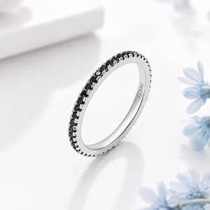 Può includere: Un anello a fascia color argento con una fila continua di piccole pietre nere a taglio rotondo incastonate lungo il bordo esterno. L'interno dell'anello presenta l'incisione d0.54ct, che indica il peso totale in carati delle pietre.