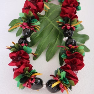 May include: A red and green lei with black beads. The lei is made of fabric flowers and is decorated with gold ribbon.