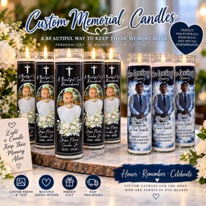 May include: A collection of cylindrical glass memorial candles featuring personalized photographs, floral graphics, and text including names, dates, and phrases like A Beautiful Soul Remembered and In Loving Memory, displayed on a wooden surface.
