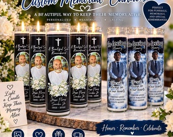 May include: A collection of cylindrical glass memorial candles featuring personalized photographs, floral graphics, and text including names, dates, and phrases like A Beautiful Soul Remembered and In Loving Memory, displayed on a wooden surface.