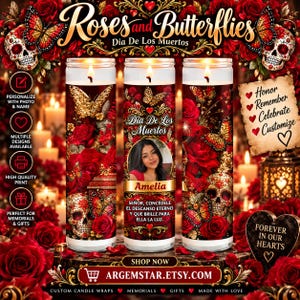 May include: Three cylindrical glass candles featuring a Dia De Los Muertos theme with red roses, gold butterflies, and decorative skulls. The center candle displays a photograph of a person, the name Amelia, and Spanish text in gold lettering.