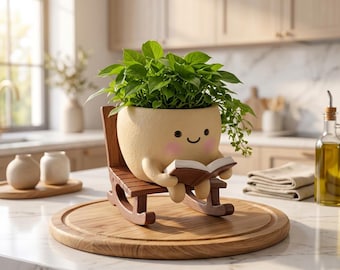 May include: A beige, round planter with a smiling face and pink cheeks, shaped like a character sitting in a small wooden rocking chair. The planter holds a lush green plant and features small arms holding an open brown book in its lap.