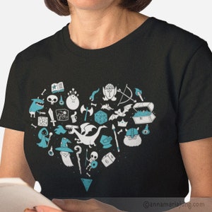May include: A black t-shirt with a blue heart-shaped design featuring various Dungeons and Dragons themed icons, including a dragon, dice, a wizard, and a chest.