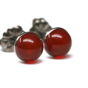 May include: A pair of silver stud earrings with red carnelian gemstones.