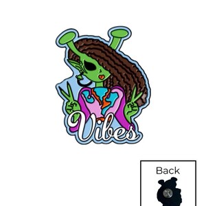 Peut inclure: Une épingle en émail colorée représentant un extraterrestre vert aux cheveux bruns, faisant le signe de la paix. L'extraterrestre porte une tenue rose et bleue, avec le mot "Vibes" en cursive. L'épingle a un dos noir avec une attache.