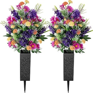 Puede incluir: Dos arreglos florales artificiales con una mezcla de flores moradas, rosas, naranjas y amarillas. Las flores están dispuestas en jarrones rectangulares negros con un patrón decorativo y una estaca para colocar en el suelo. Los jarrones miden unos 20 cm de alto.