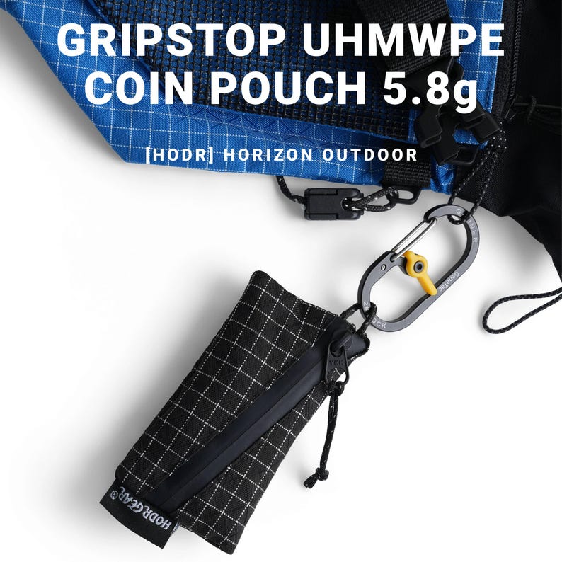 Pu&ograve; includere: Portamonete a scacchi bianchi e neri con cerniera nera e moschettone. La custodia &egrave; attaccata a un tessuto blu e nero. Il testo sulla custodia recita "HODR GEAR". Il testo "GRIPSTOP UHMWPE COIN POUCH 5.8g" &egrave; visibile.