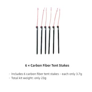May include: Six black carbon fiber tent stakes, each featuring a thin red pull cord attached to the top. The text 6 x Carbon Fiber Tent Stakes is displayed below, noting each stake weighs 3.7g and the total kit weight is 23g.