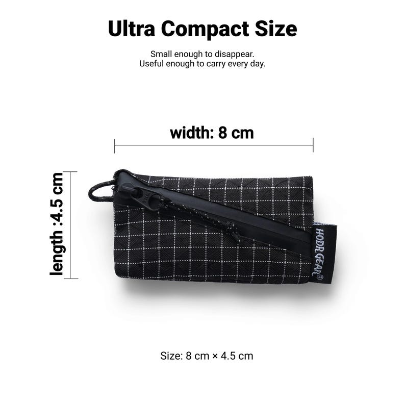 Pu&ograve; includere: Una piccola pochette a scacchi bianchi e neri con cerniera nera. Misura 8 cm di larghezza e 4,5 cm di lunghezza. Il testo recita "Ultra Compact Size" e "Small enough to disappear. Useful enough to carry every day."