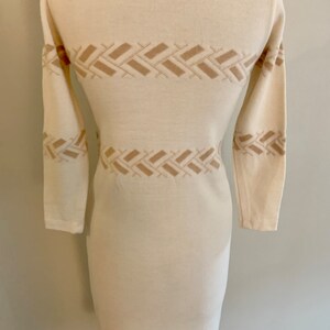 May include: A white long-sleeved sweater dress with a geometric pattern in a beige color.