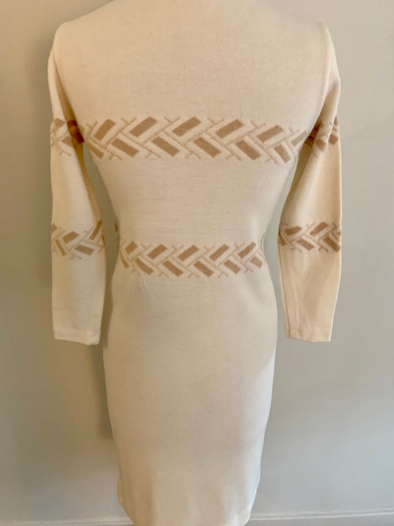 May include: A white long-sleeved sweater dress with a geometric pattern in a beige color.