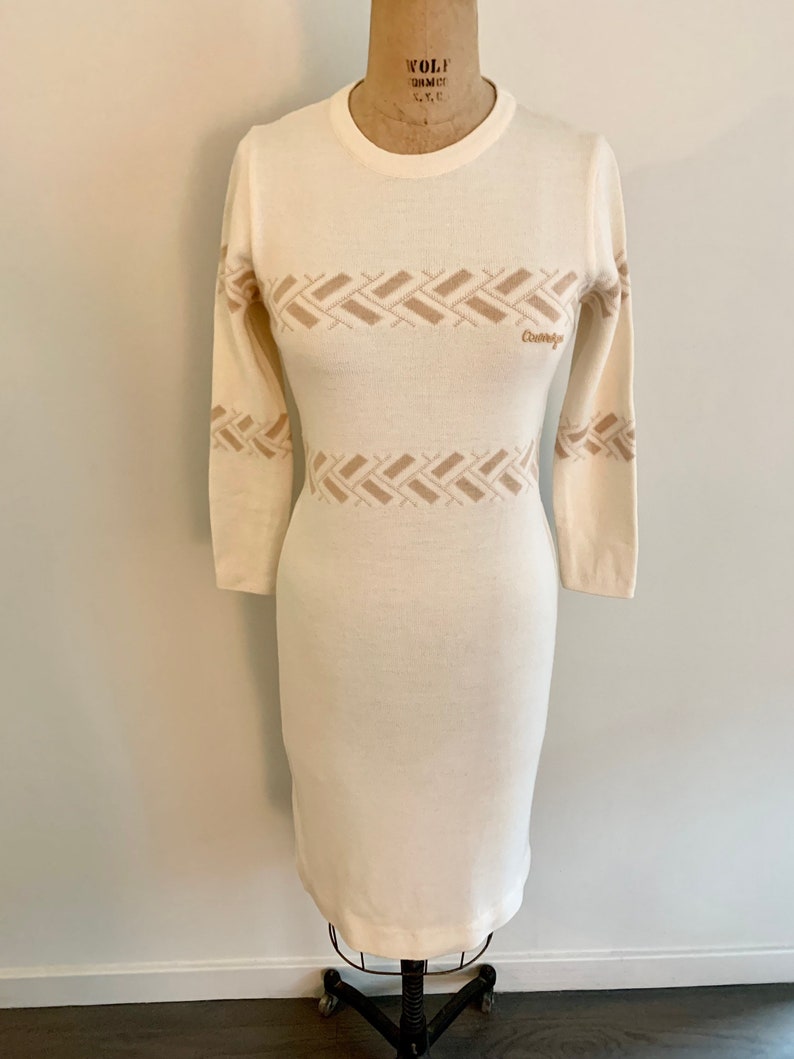 May include: A white long-sleeved sweater dress with a brown geometric pattern and the word "Couturier" embroidered on the front.