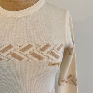 May include: A white long-sleeved sweater with a brown geometric pattern and the word "Country" embroidered on the front.