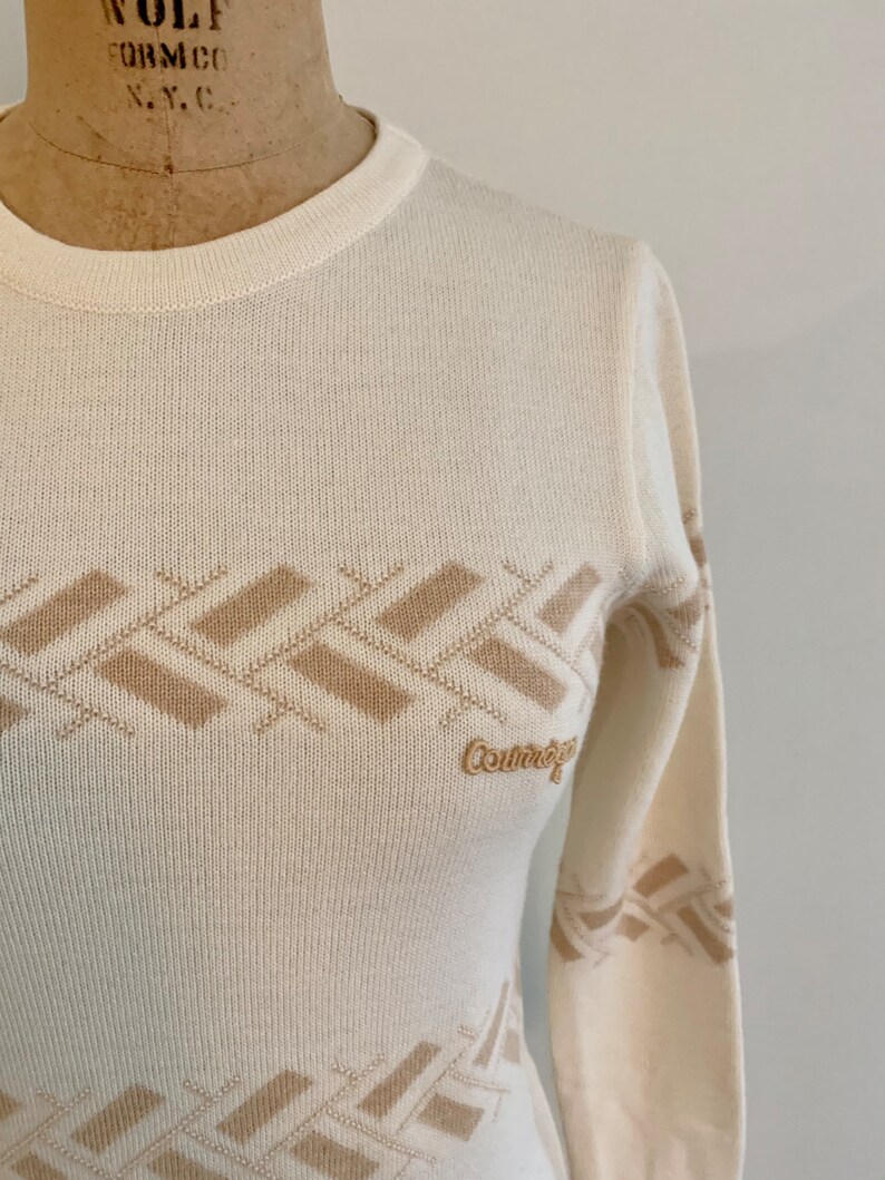 May include: A white long-sleeved sweater with a brown geometric pattern and the word "Country" embroidered on the front.