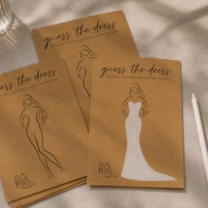 May include: Three tan paper cards featuring the text guess the dress and what will the bride wear on her big day. Each card displays a black line drawing of a figure and a pair of high heels, with one card showing a white wedding dress.