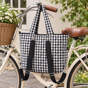 May include: A black and white gingham quilted tote bag with two top handles and adjustable black fabric backpack straps. The bag features a rectangular shape with a diamond-stitched pattern, silver-toned metal hardware, and side pockets.