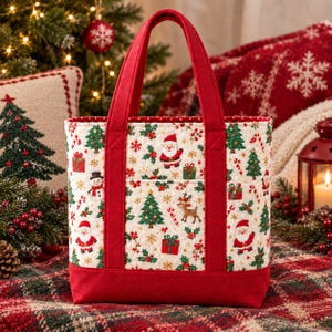 Peut inclure: Un sac fourre-tout matelassé en tissu crème avec un motif de Noël répétitif représentant le Père Noël, des rennes, des bonhommes de neige, des sapins, des cadeaux et des sucres d'orge, avec des anses et une base en tissu rouge uni.
