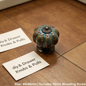 Pode incluir: Um puxador decorativo para arm&aacute;rio com um design semelhante a uma ab&oacute;bora. O puxador &eacute; uma mistura de castanho, verde-azulado e azul, com um centro de cor bronze. O puxador mede 40x40mm.