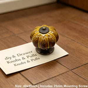 Pode incluir: Um puxador decorativo para arm&aacute;rio com um design semelhante a uma ab&oacute;bora. O puxador &eacute; principalmente amarelo e castanho com uma base e centro em bronze escuro. O texto no cart&atilde;o diz "diy & Drawer Knobs & Pulls Knobs & Pulls". O puxador mede 40x40mm.