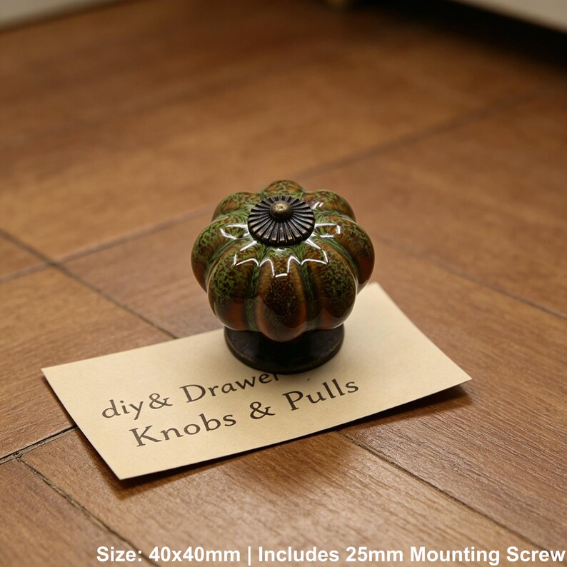 Pode incluir: Um puxador decorativo para arm&aacute;rio com design de ab&oacute;bora em tons de verde e castanho, encimado por um detalhe em metal escuro. O puxador est&aacute; sobre um cart&atilde;o que diz "diy & Drawer Knobs & Pulls". Mede 40 x 40mm.