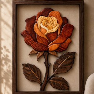 May include: A framed wall art piece featuring a layered wooden rose with petals in varying shades of deep mahogany, burnt orange, and light cream. The rose has a dark brown stem and three dark brown leaves, all encased in a dark wood frame.
