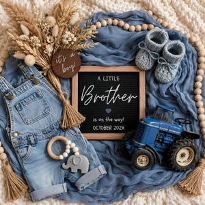May include: A blue denim overall, a pair of light blue knit booties, a blue toy tractor, a wooden elephant teether, and a dried floral arrangement. A wooden sign reads "it's a boy!" and a letter board displays "A LITTLE Brother is on the way! OCTOBER 202X".