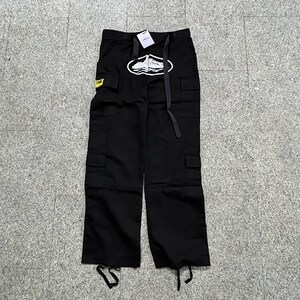 Puede incluir: Pantalones cargo negros con m&uacute;ltiples bolsillos y un gr&aacute;fico blanco en la pierna izquierda. Los pantalones tienen cintura con cord&oacute;n y una etiqueta amarilla con texto. El gr&aacute;fico tiene forma ovalada con un dise&ntilde;o de barco.