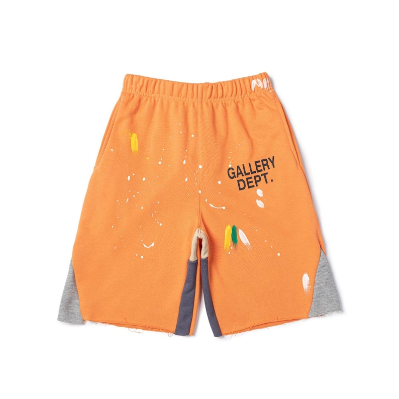 May include: Orange shorts with paint splatter details and the text "GALLERY DEPT." in black. The shorts have grey panels on the sides and a drawstring waistband. The shorts are made of a soft, comfortable material.
