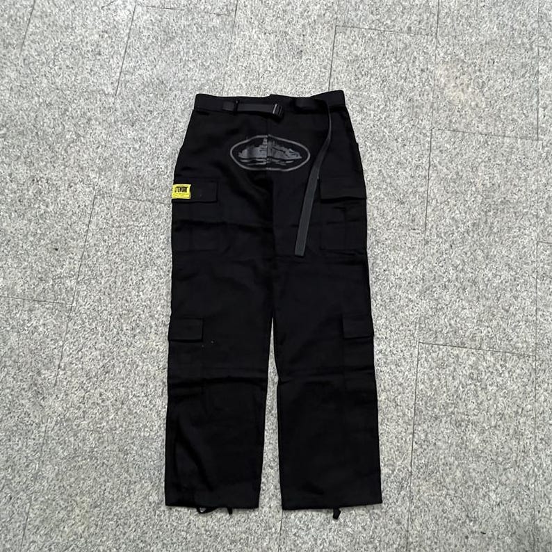 Puede incluir: Pantalones cargo negros con m&uacute;ltiples bolsillos y cintur&oacute;n. Los pantalones tienen un logotipo en la parte delantera y una peque&ntilde;a etiqueta amarilla. Fabricados con un material duradero, adecuados para diversas actividades.