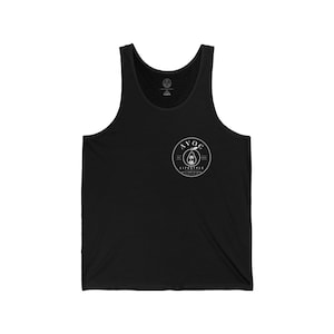 May include: Black tank top with a round white logo on the chest. The logo features the text "AVOC LIFESTYLE" around an avocado graphic. The tank top has a scoop neck and is made of a soft material.