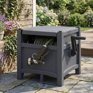 May include: A dark gray garden hose reel with a hand crank and a nozzle. The reel is rectangular with a slatted front and is sitting on a stone patio. The background includes plants and a wooden structure.