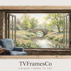 Puede incluir: Una obra de arte enmarcada que representa un paisaje sereno visto a través de una ventana abierta. La escena incluye un puente de piedra sobre un río, exuberante vegetación y un sillón azul. El marco es de color marrón claro.