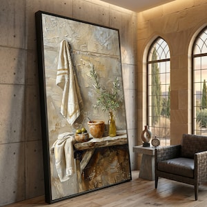 May include: A framed canvas art print depicts a still life scene. A white towel with gold stripes hangs above a wooden table. On the table are a bowl of olives, a ceramic pot, and a glass bottle with green sprigs.