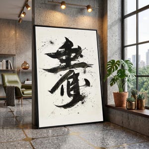 May include: Large framed artwork featuring bold black Japanese calligraphy on a white background with ink splatter. The artwork is displayed in a modern interior setting, leaning against a concrete wall. The frame is black.