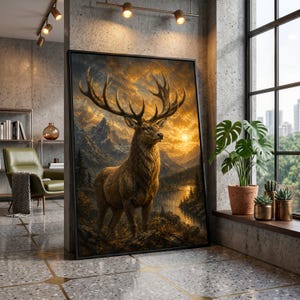 Puede incluir: Una impresión en lienzo enmarcada que presenta un majestuoso ciervo con grandes cuernos, sobre un fondo de un paisaje montañoso y una puesta de sol. La obra de arte se exhibe en un interior moderno, apoyada contra una pared de hormigón.