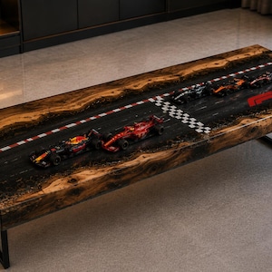 May include: A rectangular coffee table featuring a live-edge wood border and a central resin inlay depicting a Formula 1 racetrack. The design includes miniature race cars, a checkered finish line, red and white curbing, and a red F1 logo.
