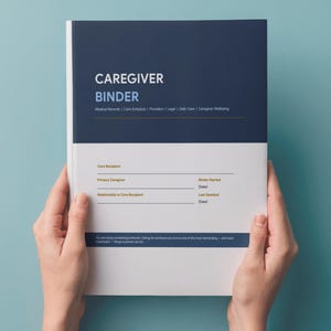 May include: A caregiver binder with a navy blue and white cover is held by two hands. The cover reads "Caregiver Binder" with sections for medical records, care schedule, and daily care. The binder is designed to help organize caregiving information.