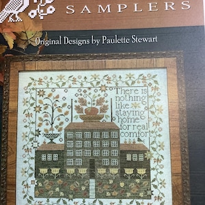 May include: A cross-stitch pattern titled Plum Street Samplers by Paulette Stewart. The design features a dark green house with a central tower, surrounded by a floral border and the text: There is nothing like staying home for real comfort.